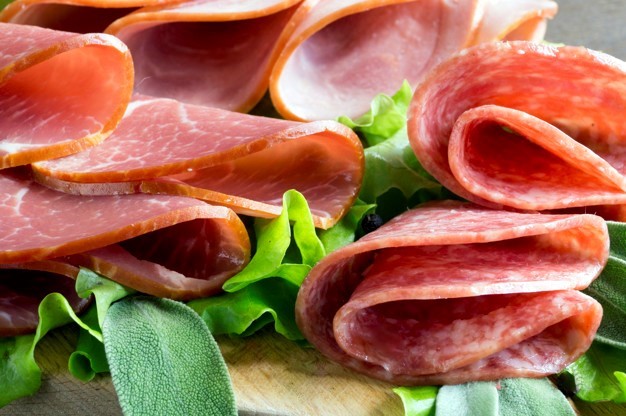 slices of French cheese-dried salami with spices on wooden backg